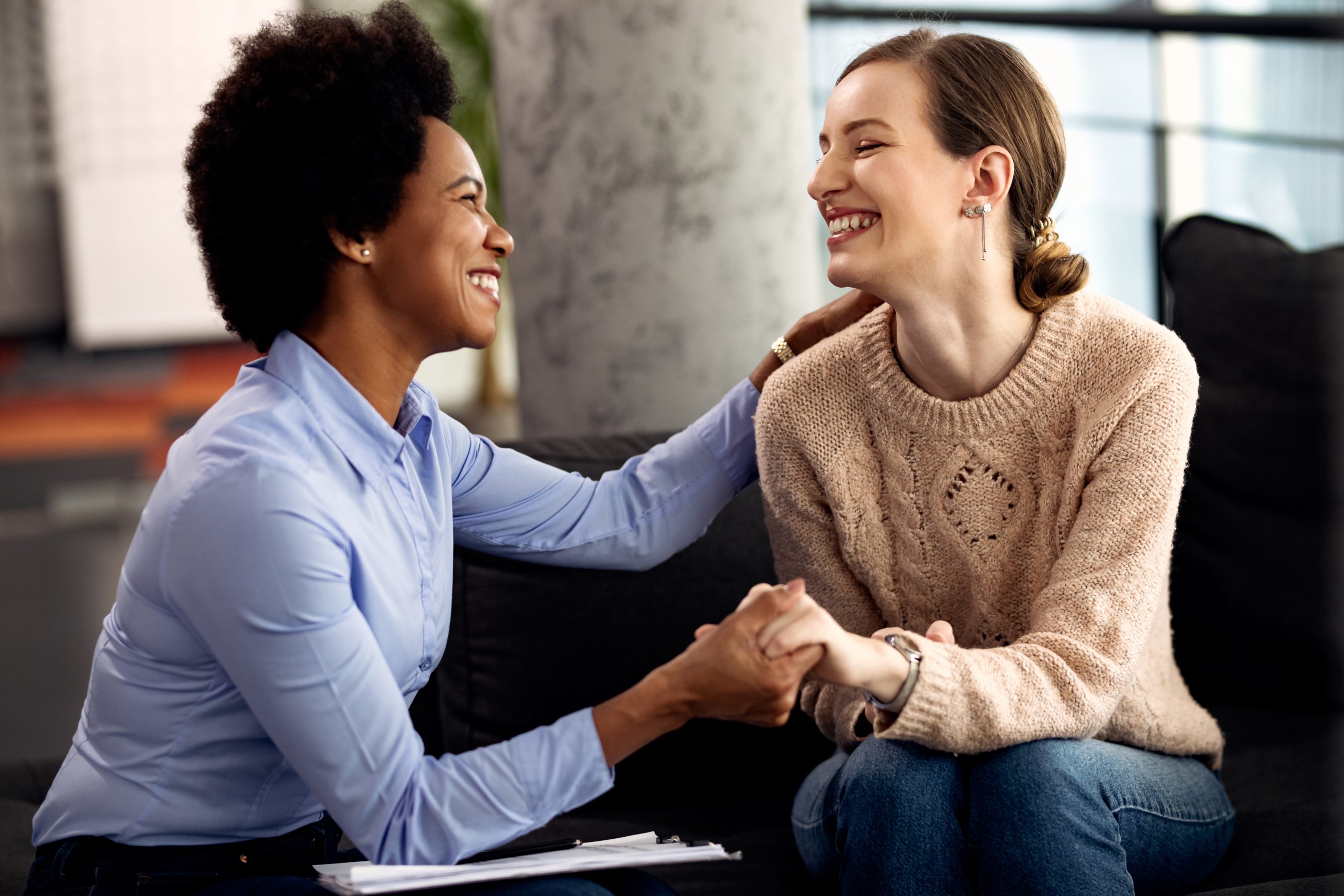 I always feel relieved after a session with you! Young happy woman holding hands with her psychotherapist during an appointment at the clinic.